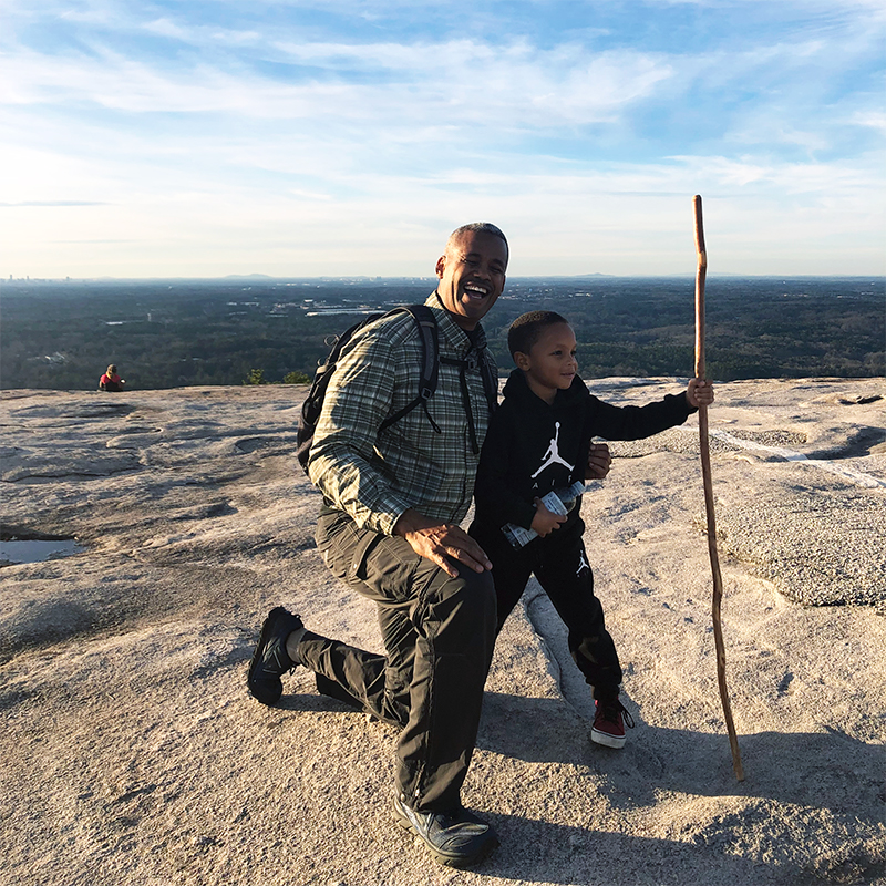 man and grandson pose for picture after hiking up stone mountain